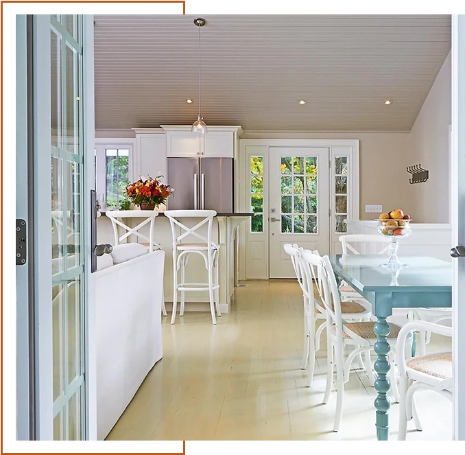 A kitchen with white walls and floors, and a dining room table.