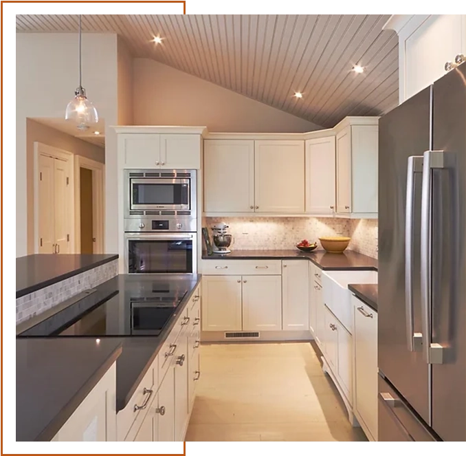 A kitchen with white cabinets and black counter tops.