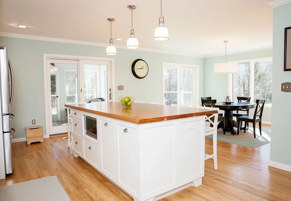 A kitchen with wooden floors and white cabinets.