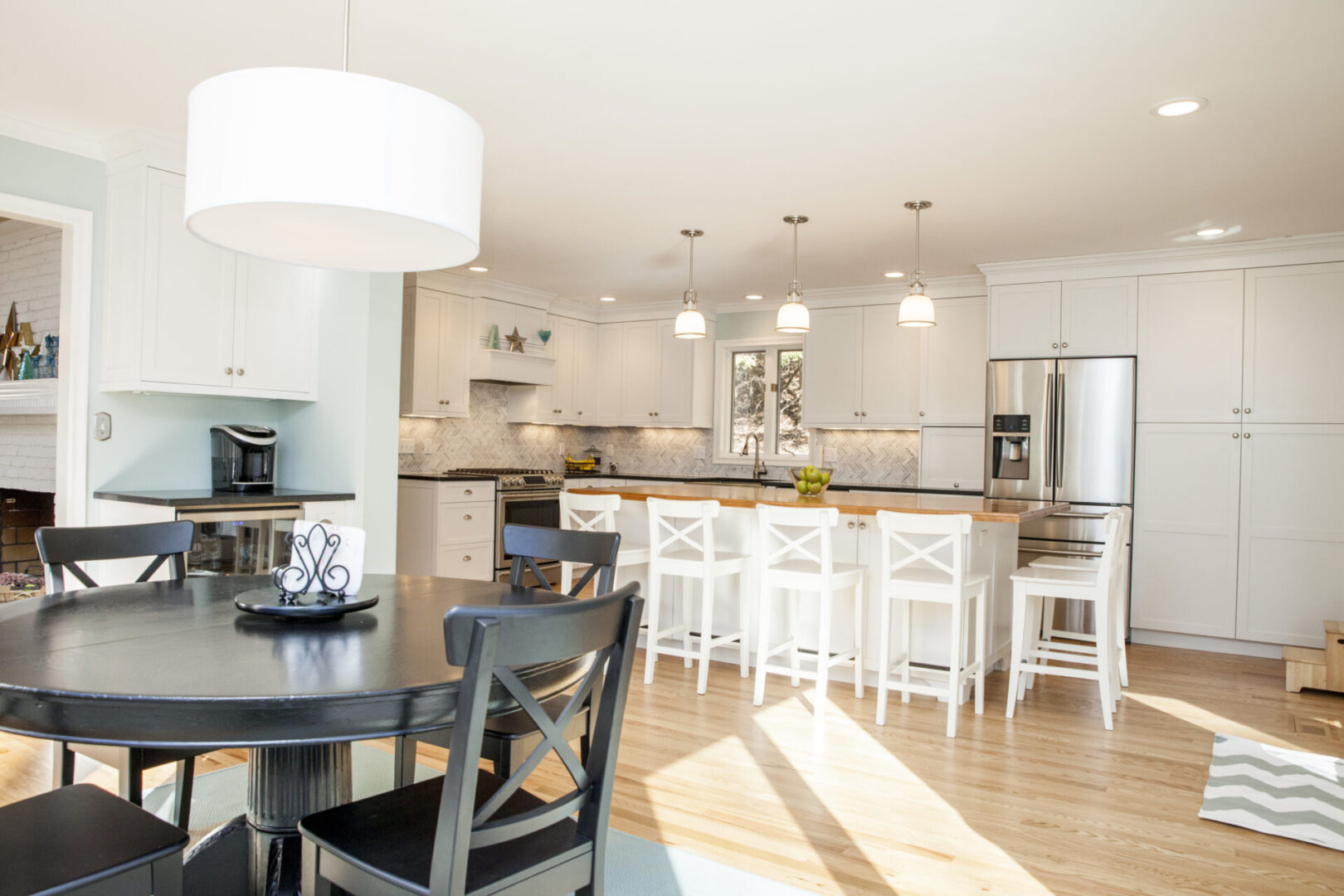 A kitchen with white cabinets and black chairs.