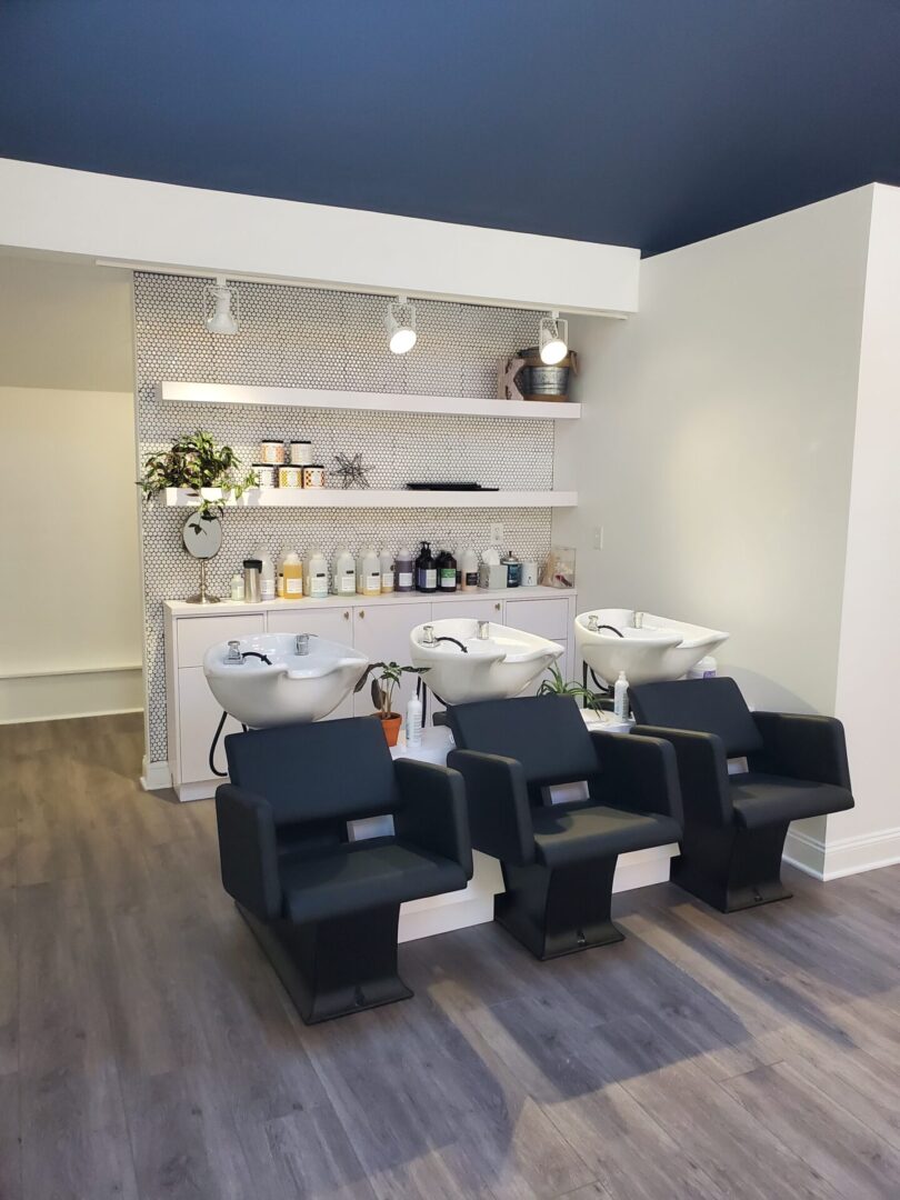 A room with three black chairs and some shelves