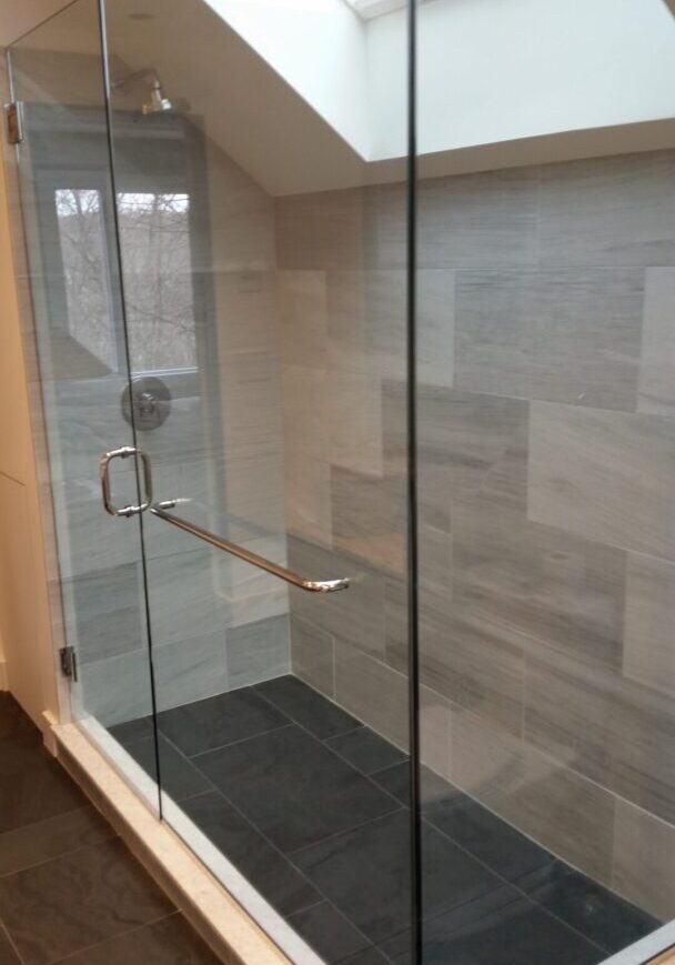 A glass shower door with a black mat in the middle of it.